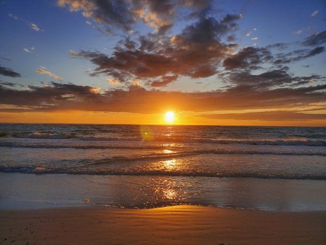 The sun is setting over the ocean and reflected in the water