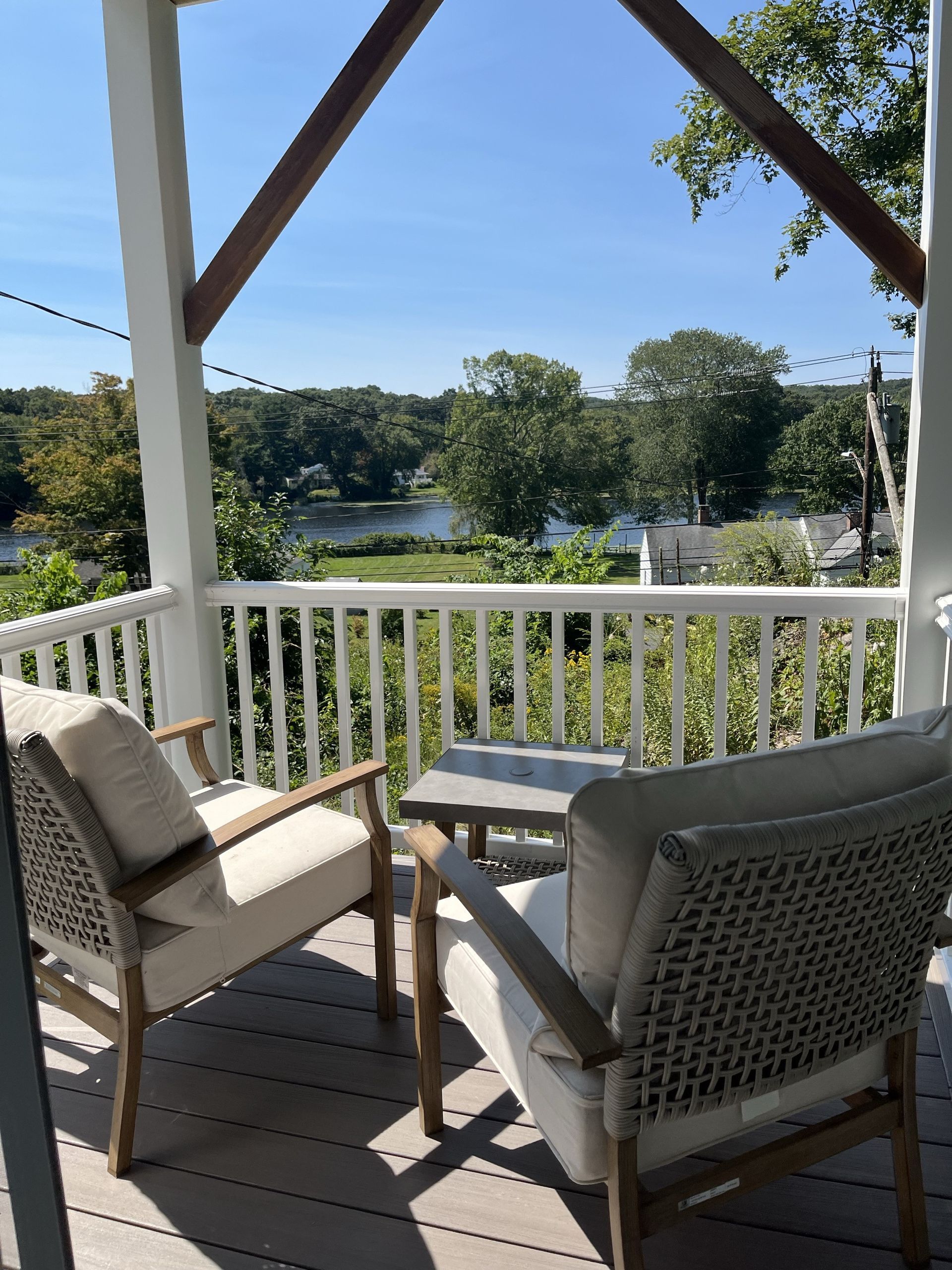A porch with two chairs and a table overlooking a body of water