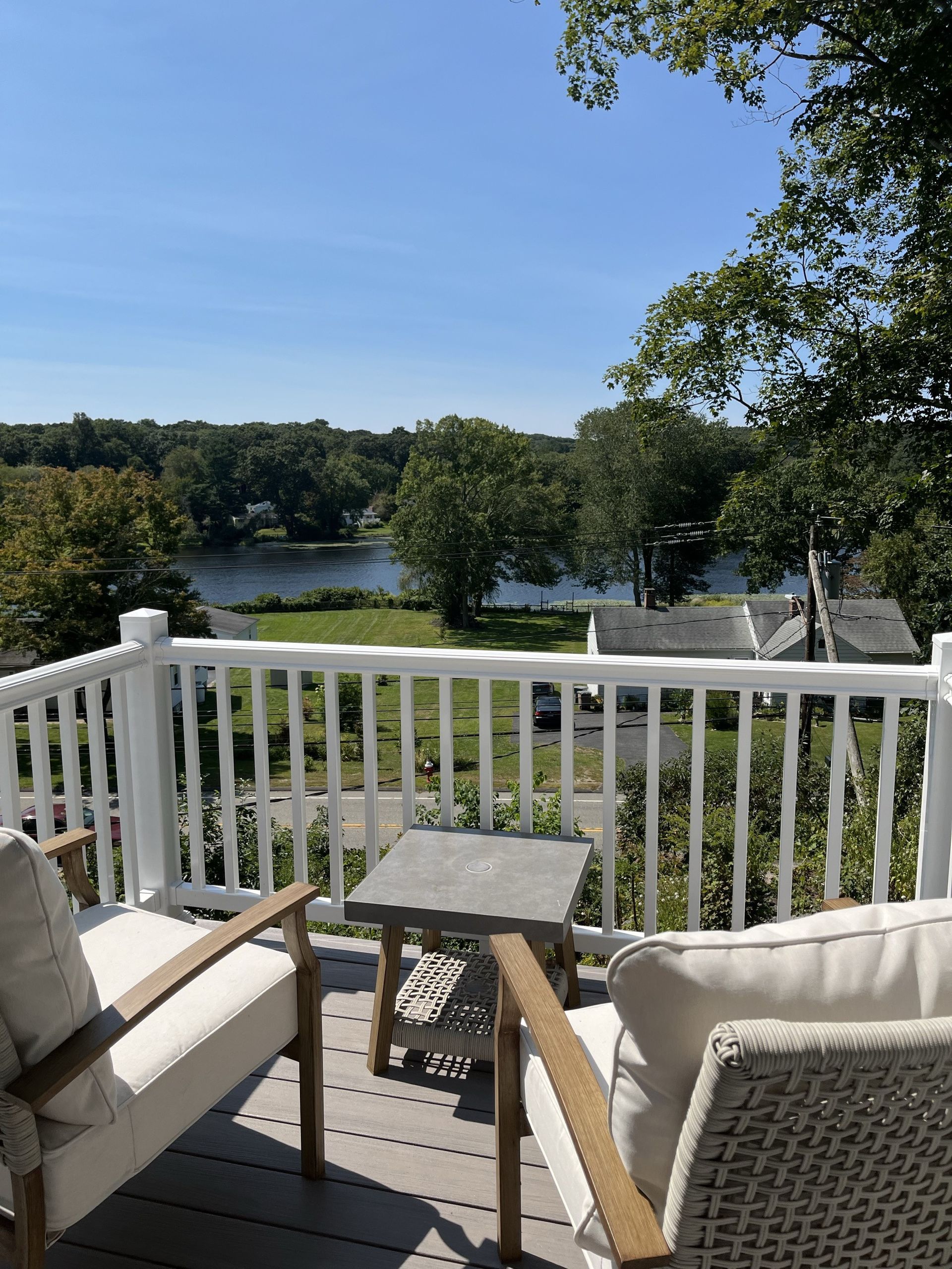 A balcony with two chairs and a table overlooking a lake