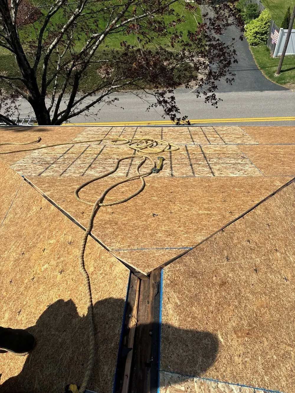 View of a roof under construction, with exposed wood panels, a valley, and a street in the background.