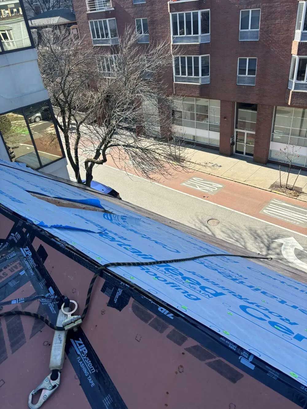 Rooftop view of a street, with a safety harness and buildings in the background.
