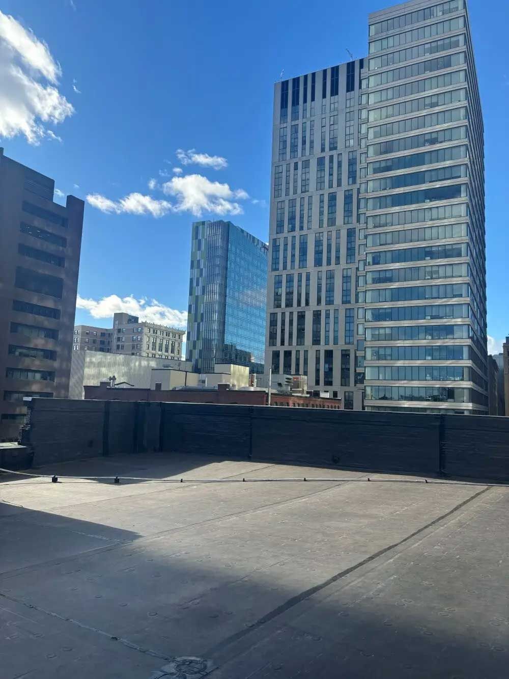 Rooftop view of a city skyline with tall, modern buildings under a bright blue sky.