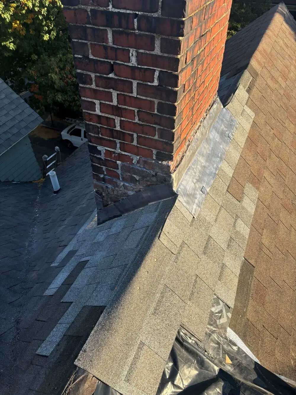 Brick chimney on a shingled roof, flashing visible.