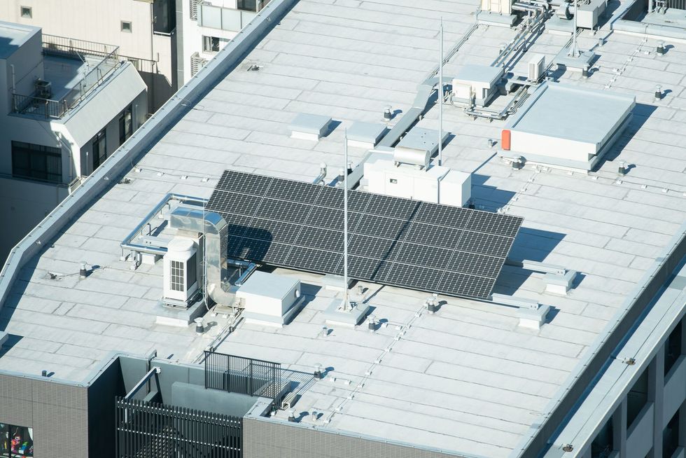 Solar panels on a building rooftop. Grey, blue, and white colors.