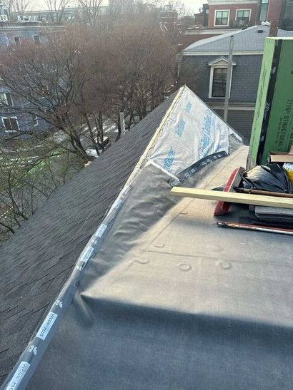 Roof with shingles under repair, featuring a silver tarp, black underlayment, and construction tools.