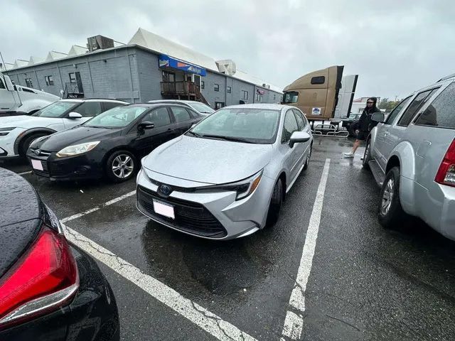 Silver Toyota Corolla in a wet parking lot, near other cars and a building.