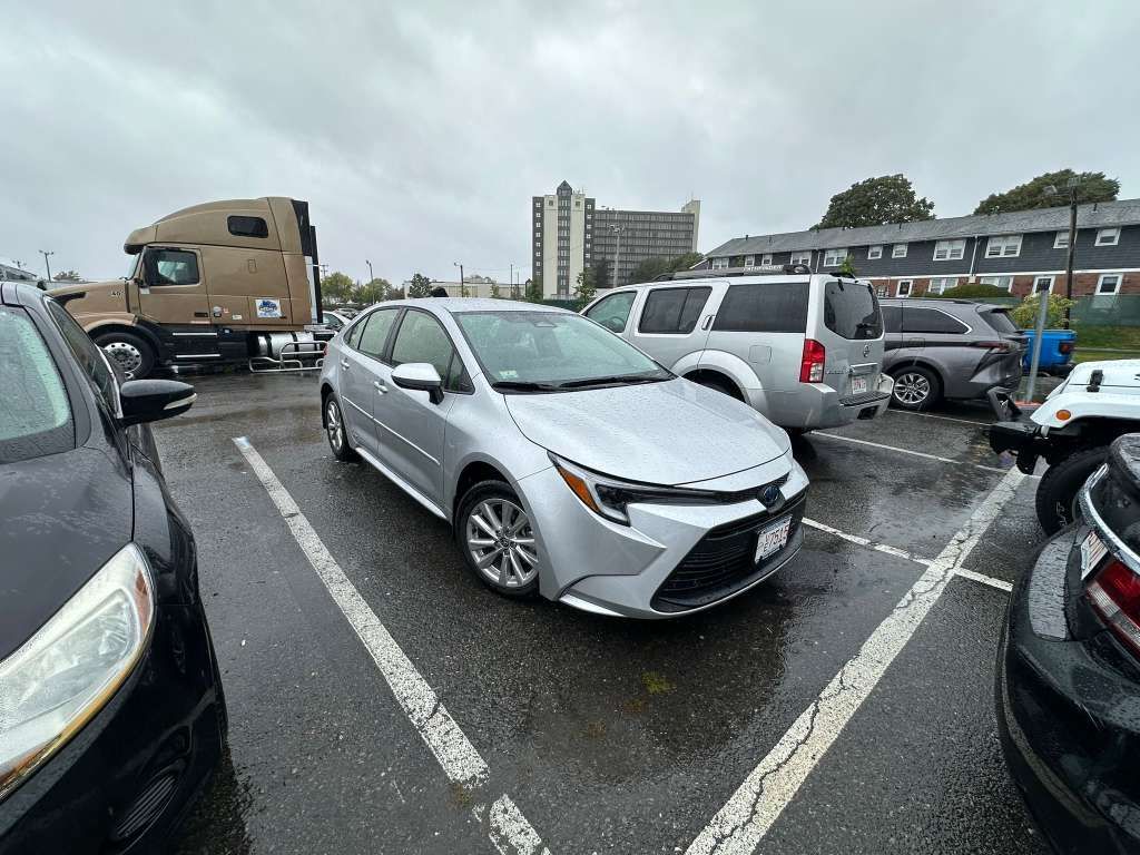 Silver Toyota Corolla parked in a lot; rainy day.