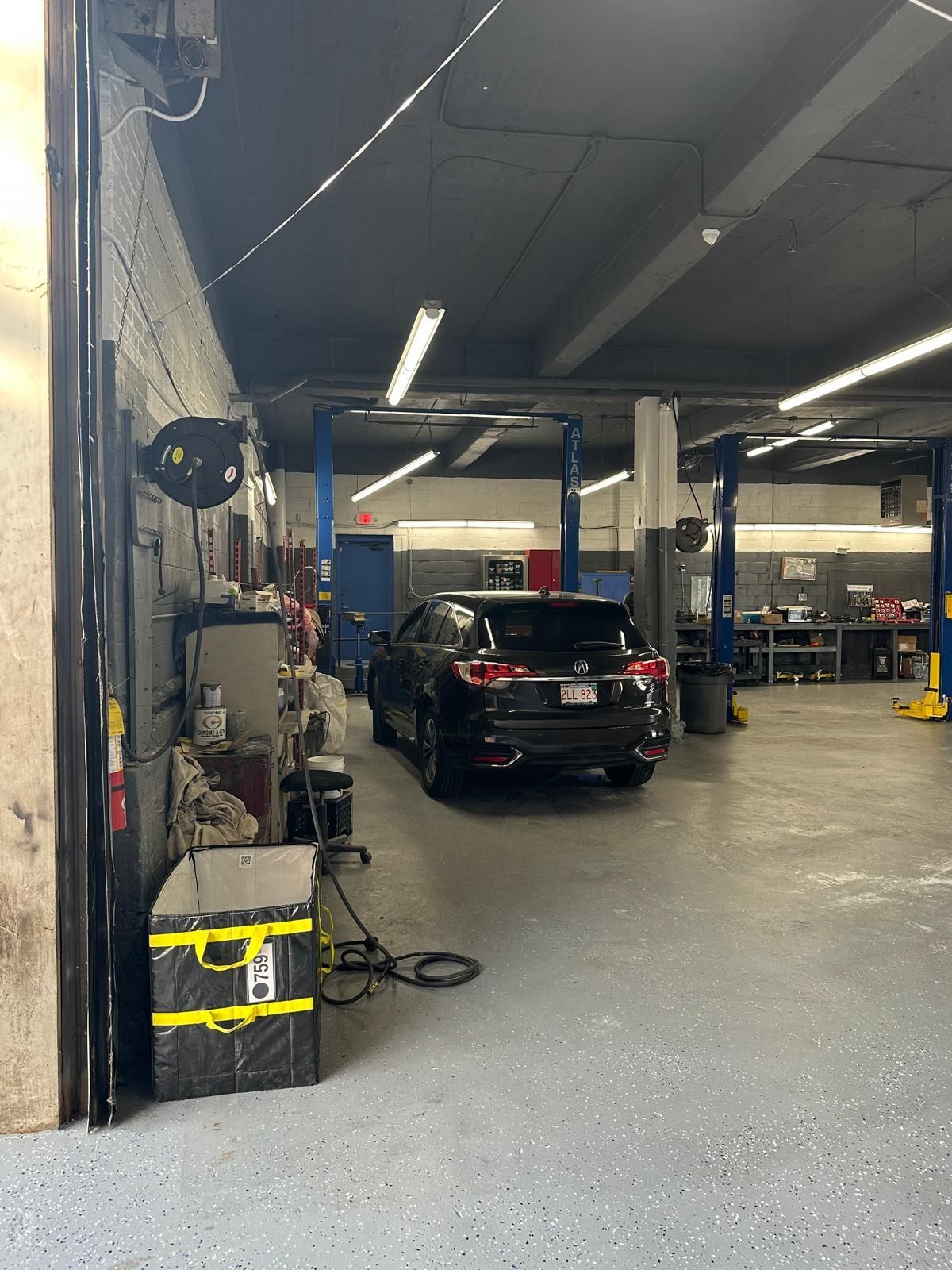 Black SUV inside a garage, next to tools and equipment.