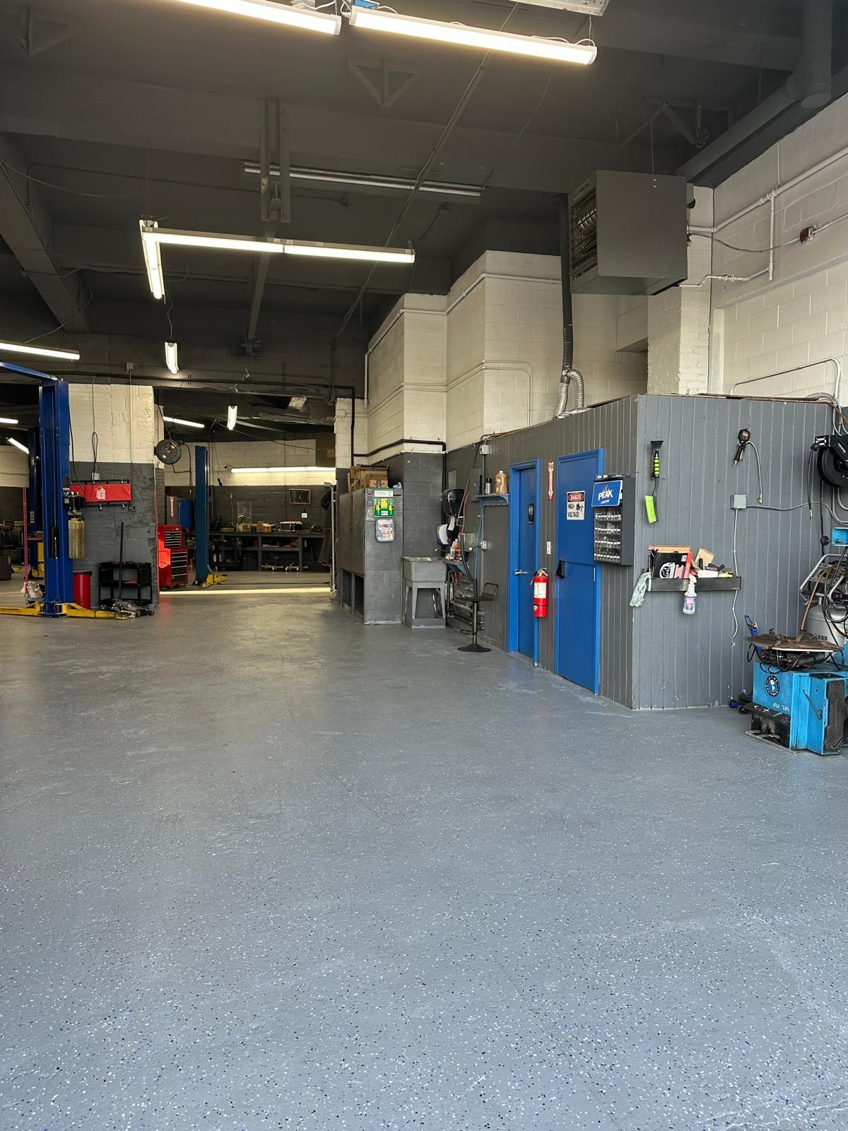 Garage interior with blue doors, gray walls, and equipment. Empty space with a painted floor.