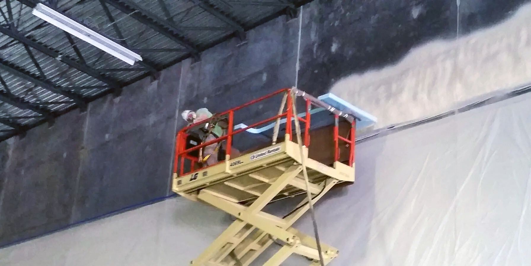 a man is standing on a scissor lift in a warehouse
