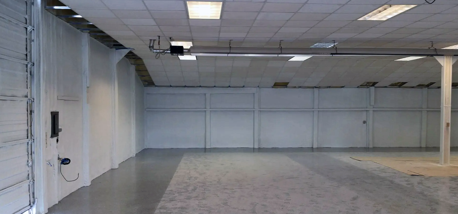an empty warehouse with white walls and a concrete floor