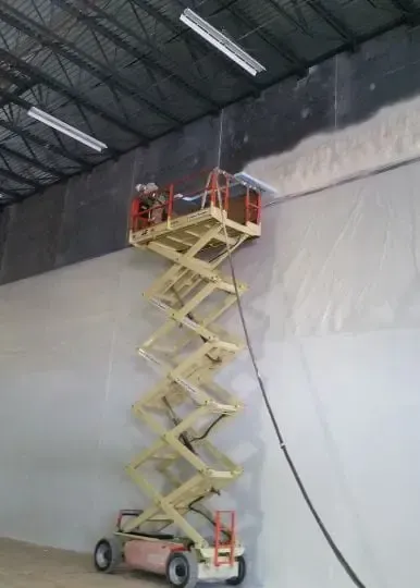 a man is standing on a scissor lift in a warehouse