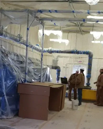 a group of people are standing in a room with a lot of pipes