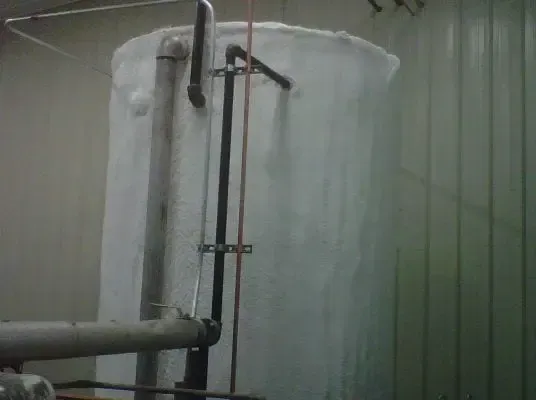 a large white tank with pipes attached to it in a room