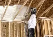 a man is spraying insulation on the ceiling of a house under construction