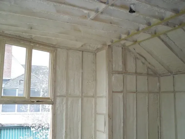 a room with a window and walls covered in white spray foam