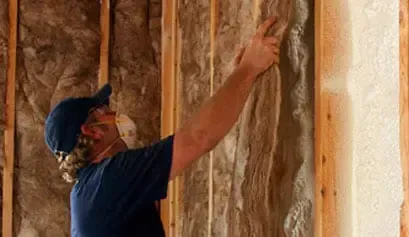 a man wearing a mask is insulating a wall