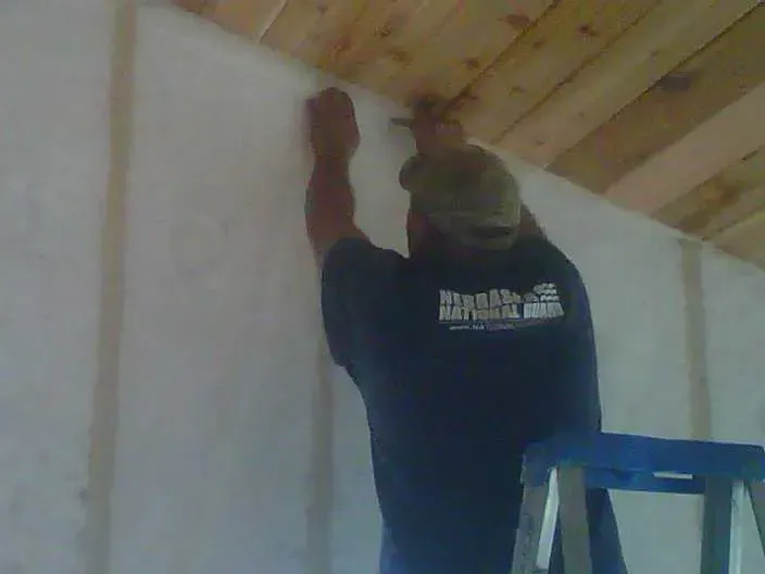 a man is standing on a ladder working on a wall