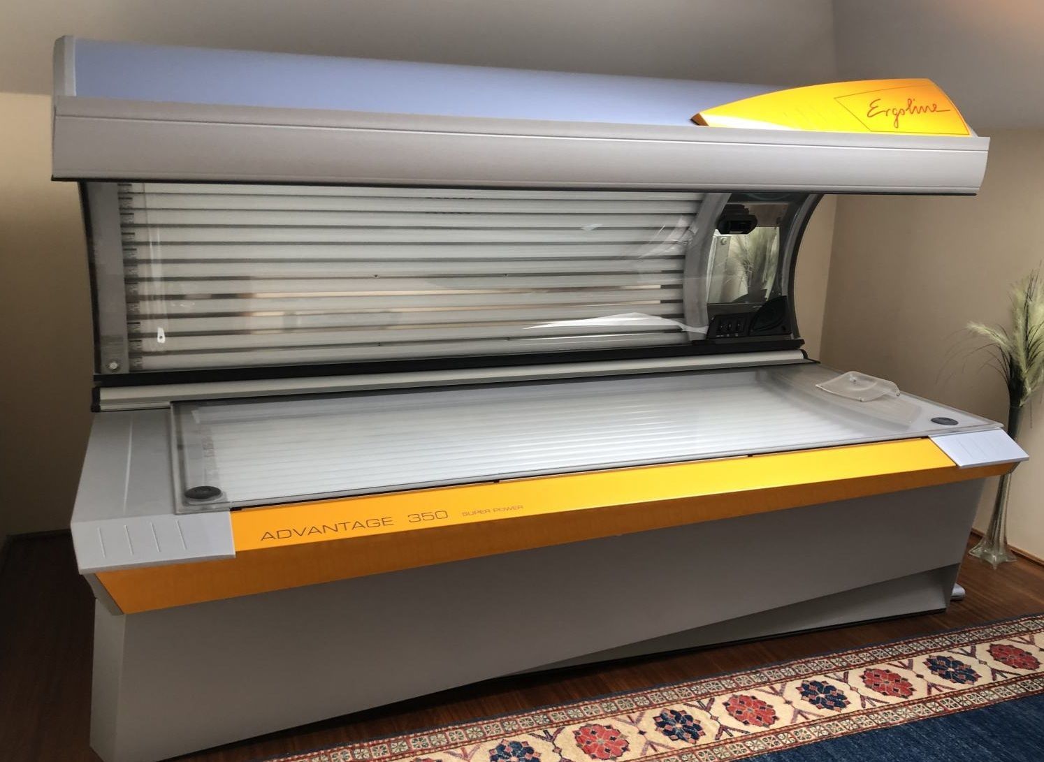 Open tanning bed with gray and orange exterior in a salon room
