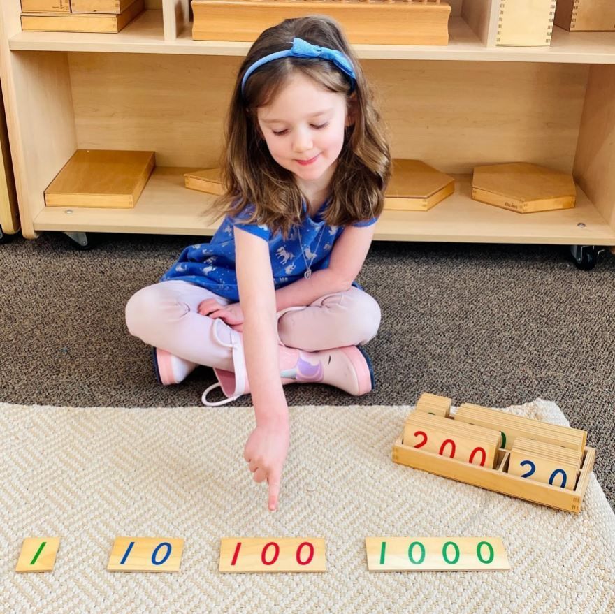 A little girl is sitting on the floor playing with numbers