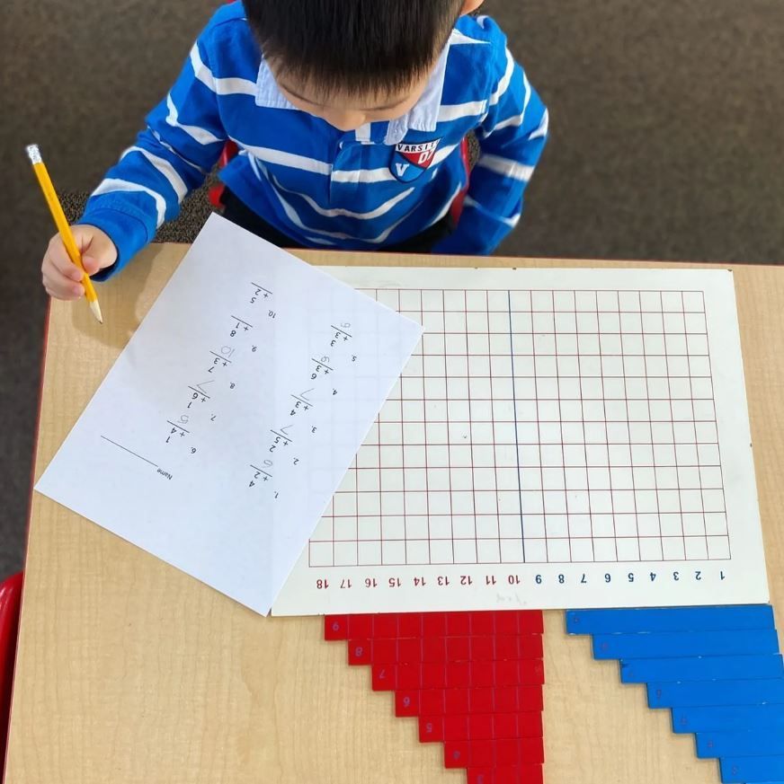A young boy is writing on a piece of paper with a pencil