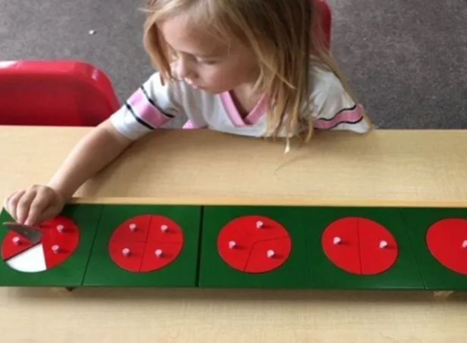 A little girl is playing with a green box with red circles on it