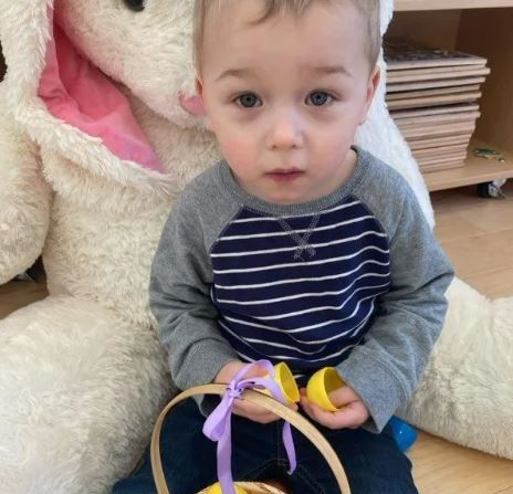 A little boy is sitting and holding an easter basket
