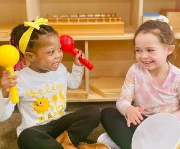 Two little girls playing with musical instruments.