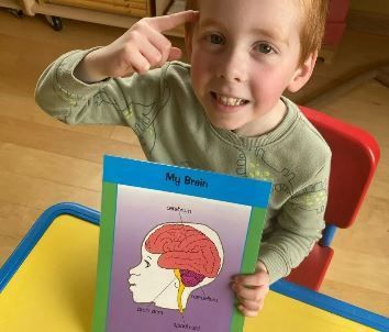 A young boy is sitting at a table holding a picture of his brain