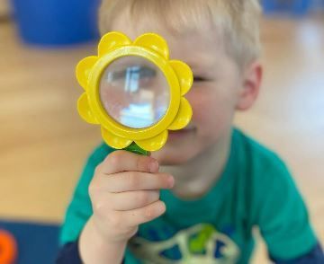 A young boy is holding a magnifying glass in his hand