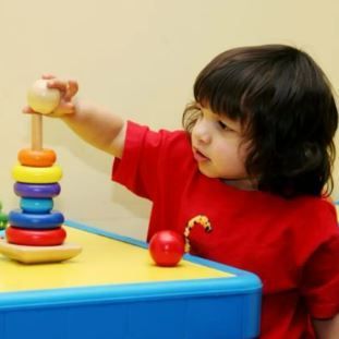 A little girl is playing with a stacking toy