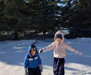 A boy and a girl are standing in the snow 