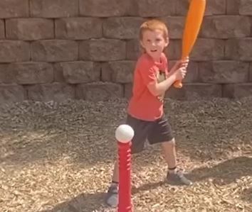 A young boy is swinging a baseball bat at a ball