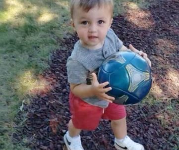 A little boy is holding a blue soccer ball in his hands.