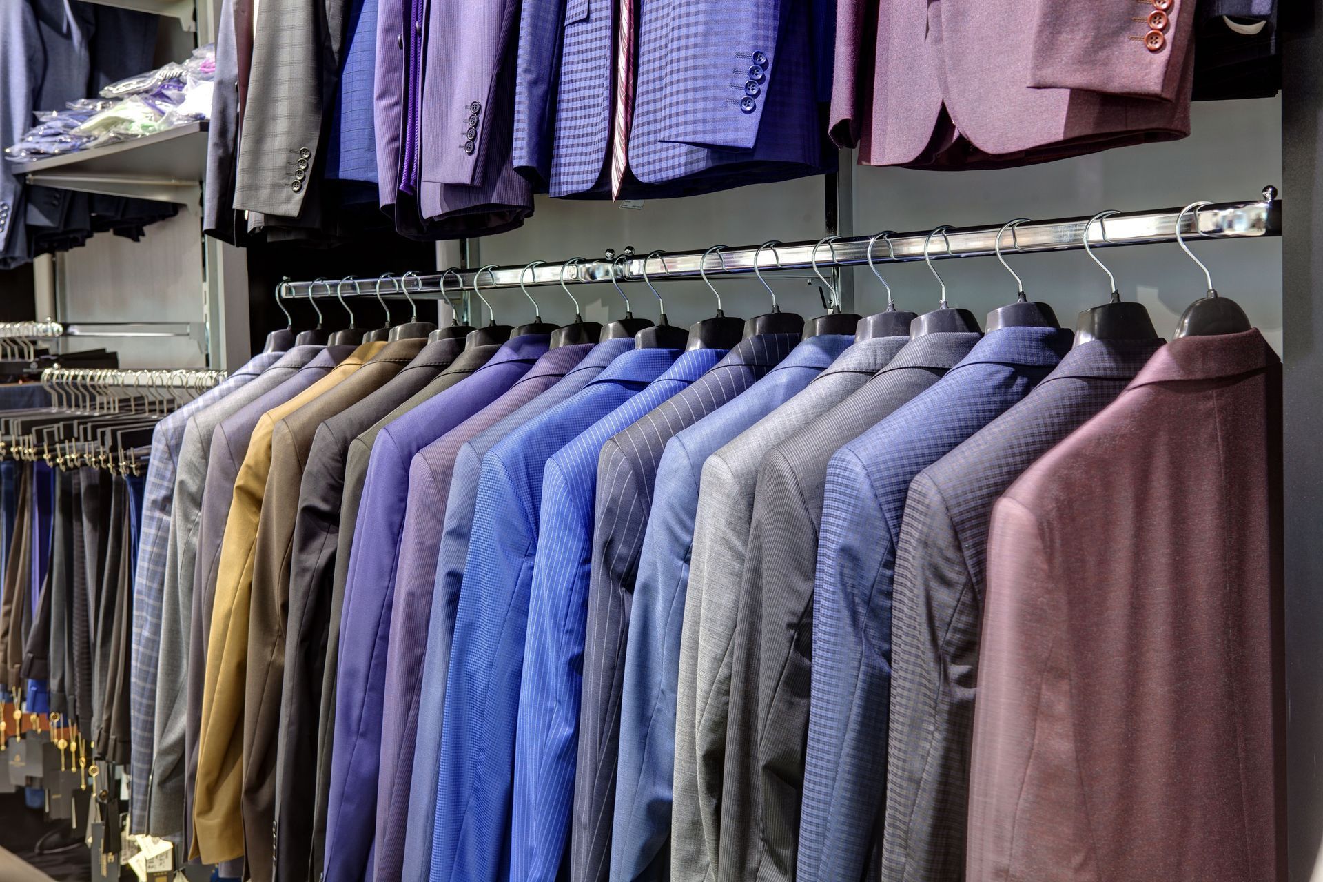 Clothing rack with neatly arranged shirts and jackets in blue, purple, and gray tones.