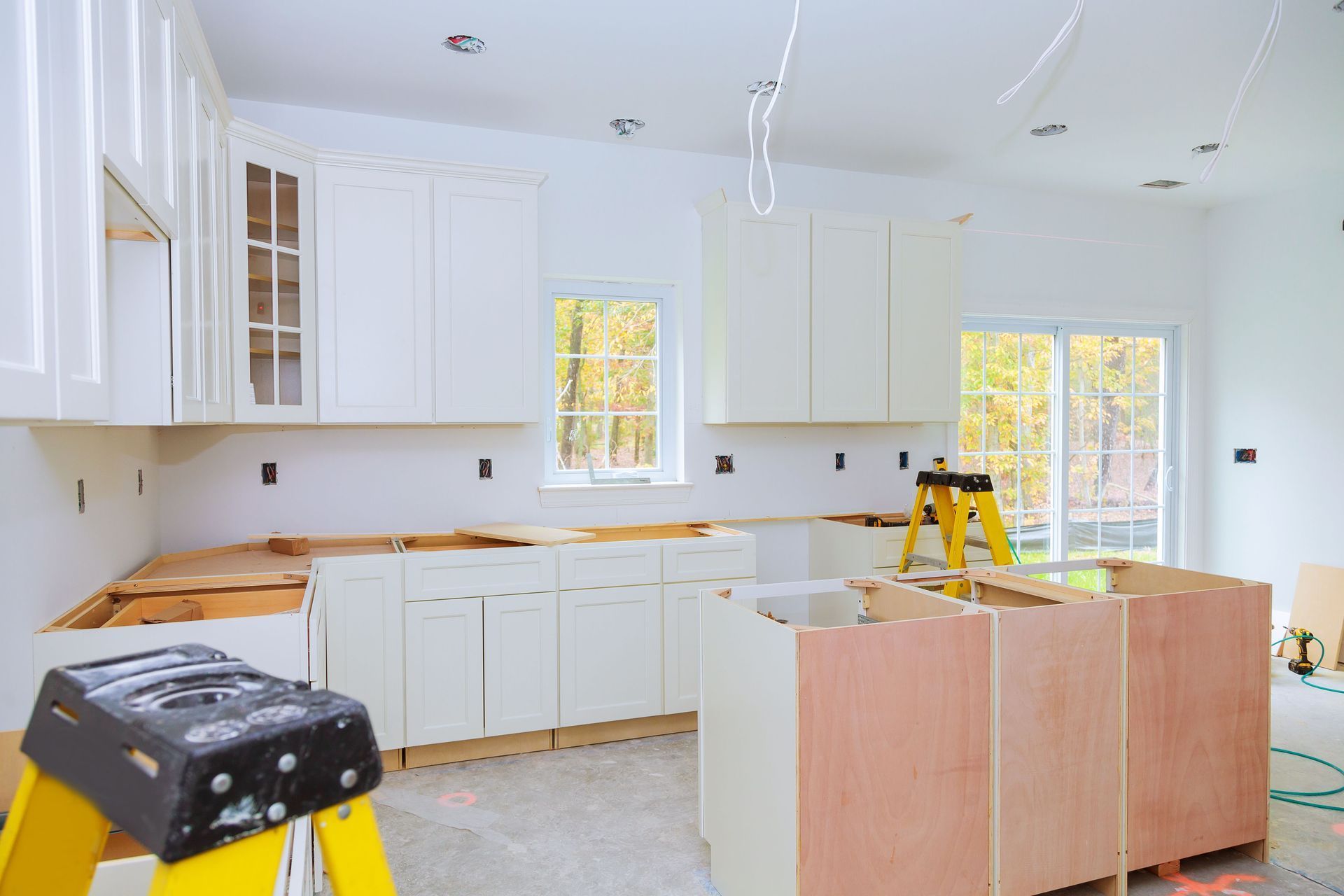 Bright white kitchen under renovation with cabinets installed and tools on countertops