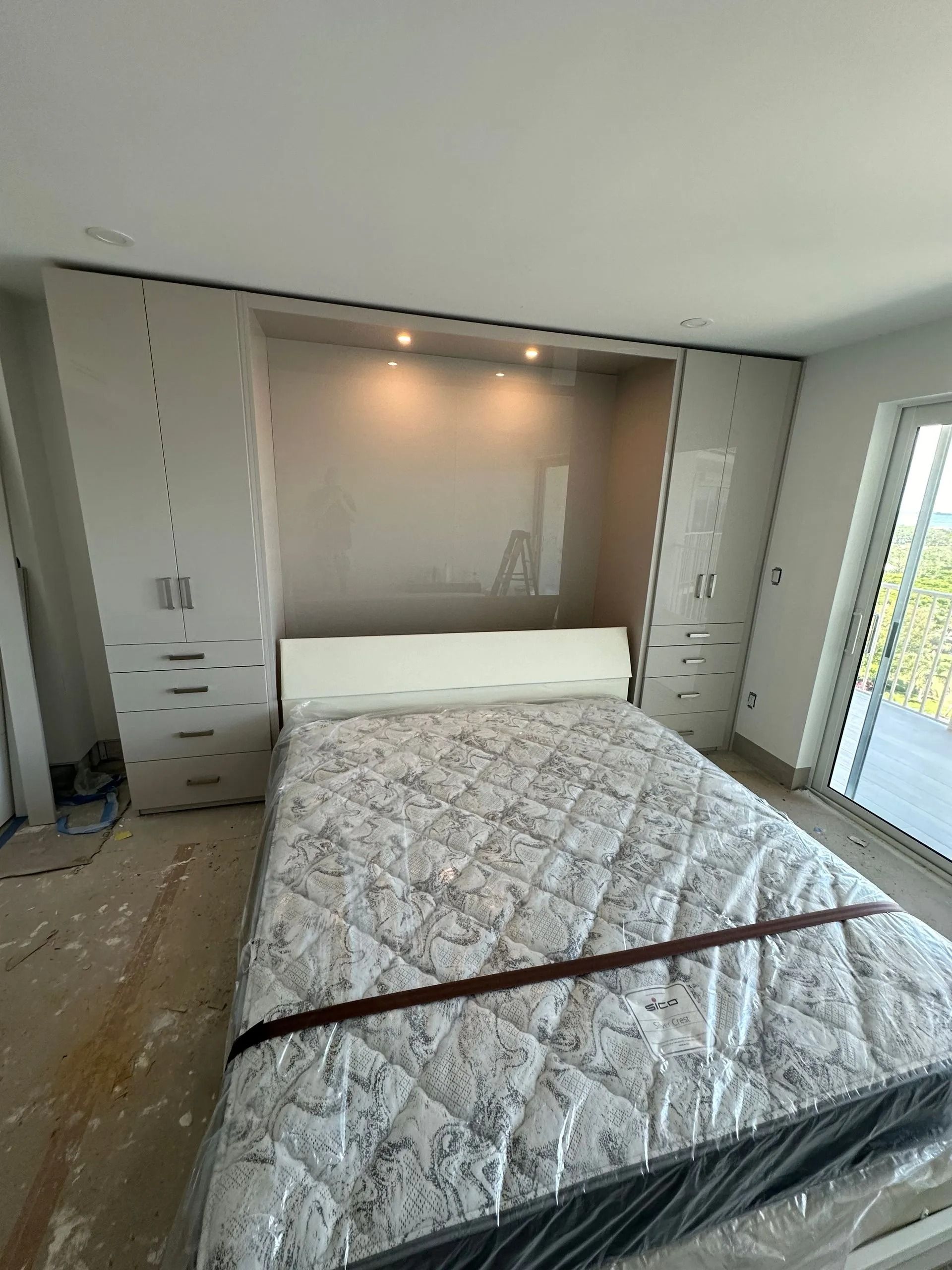 Modern bedroom with a bed, built-in closets, and a large window view