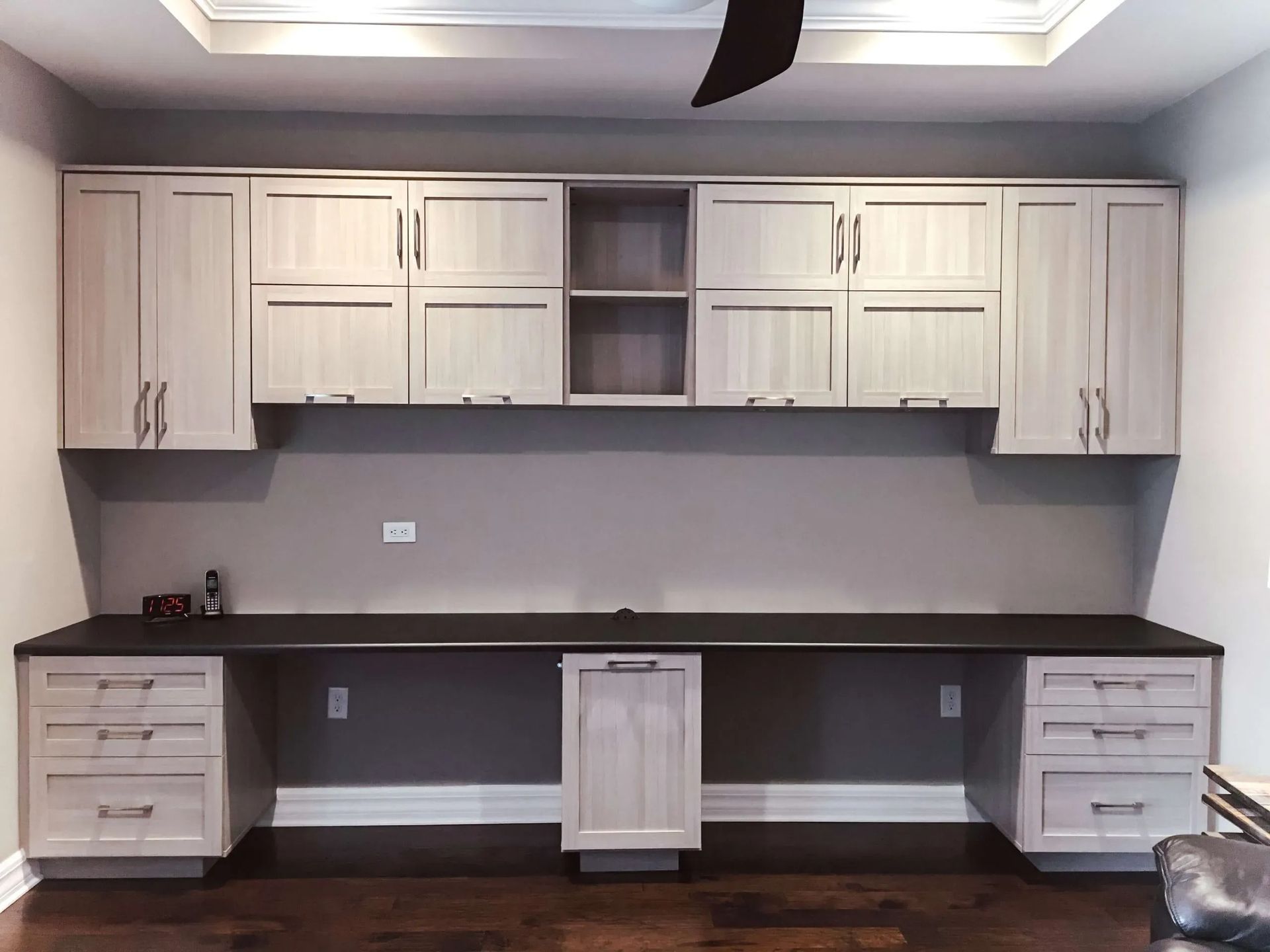 Built-in kitchen cabinets with dark countertop and white shaker doors in a gray room.