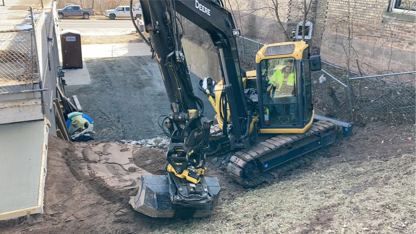 A yellow and black excavator is digging a hole in the ground.