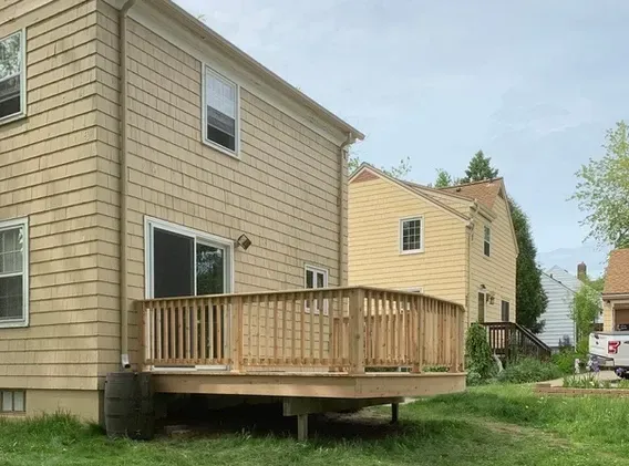 A house with a wooden deck in front of it.