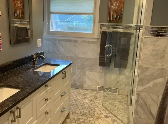 A bathroom with a sink , mirrors , and a walk in shower.