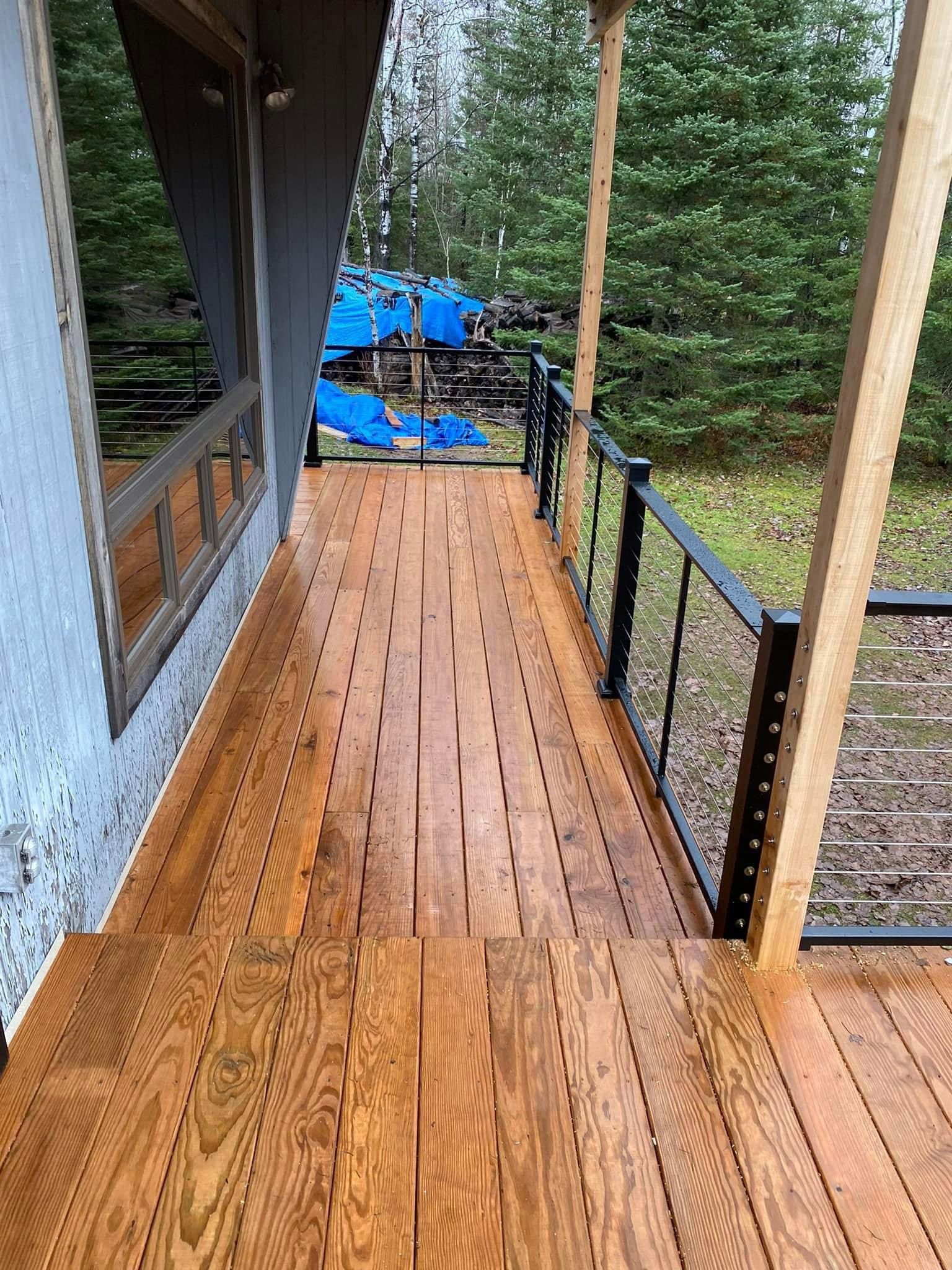 A wooden deck with a metal railing and stairs leading up to it.