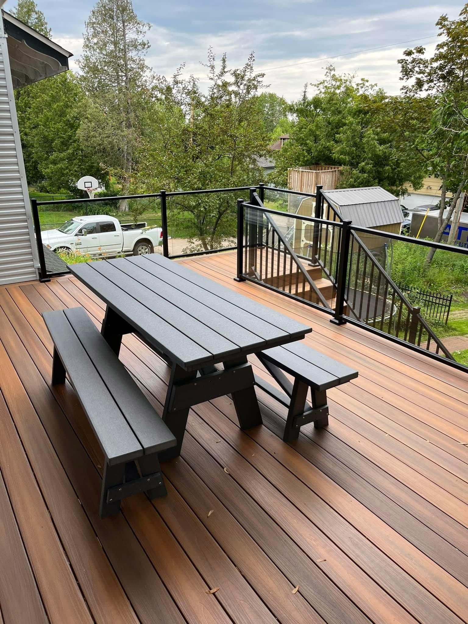 A wooden deck with a picnic table and benches on it.