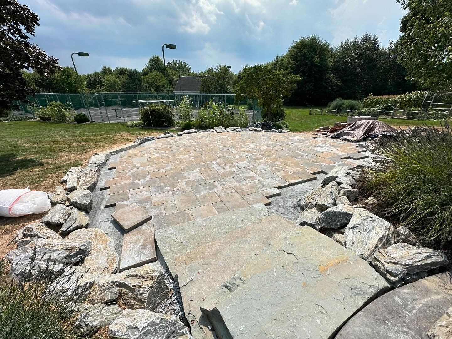 Stone path under construction in a grassy park, with broken concrete slabs and rubble