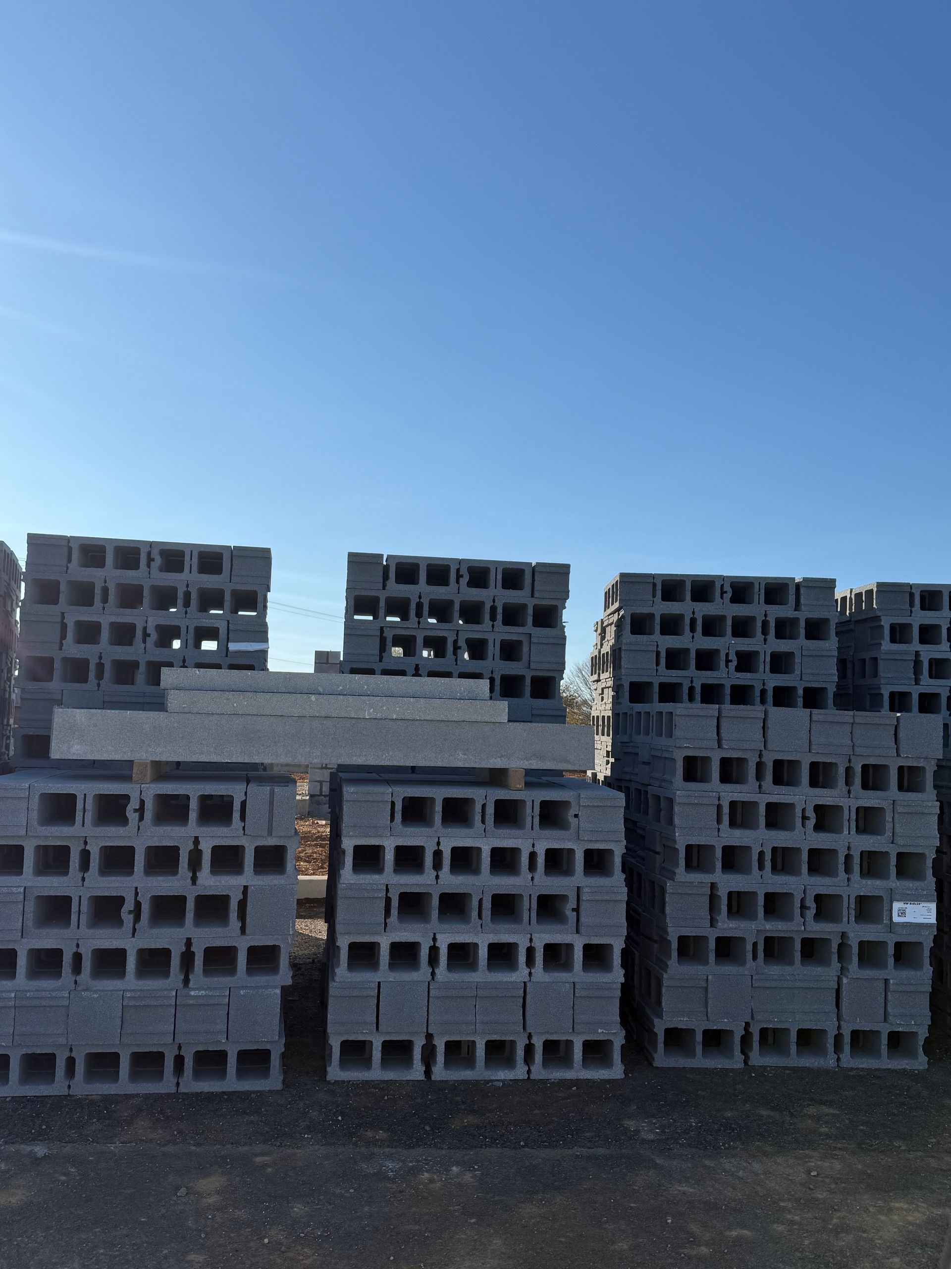 Stacks of gray cinder blocks outdoors under a clear blue sky