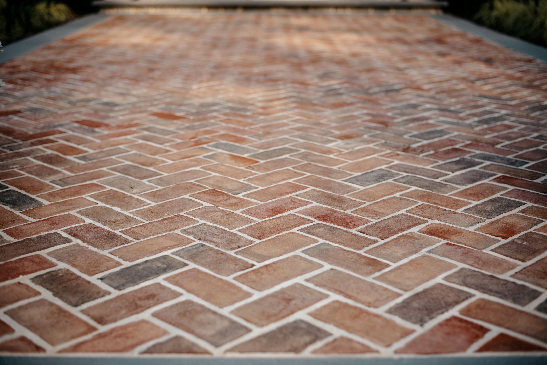 Red brick herringbone walkway stretching into the distance, with a blurred background.