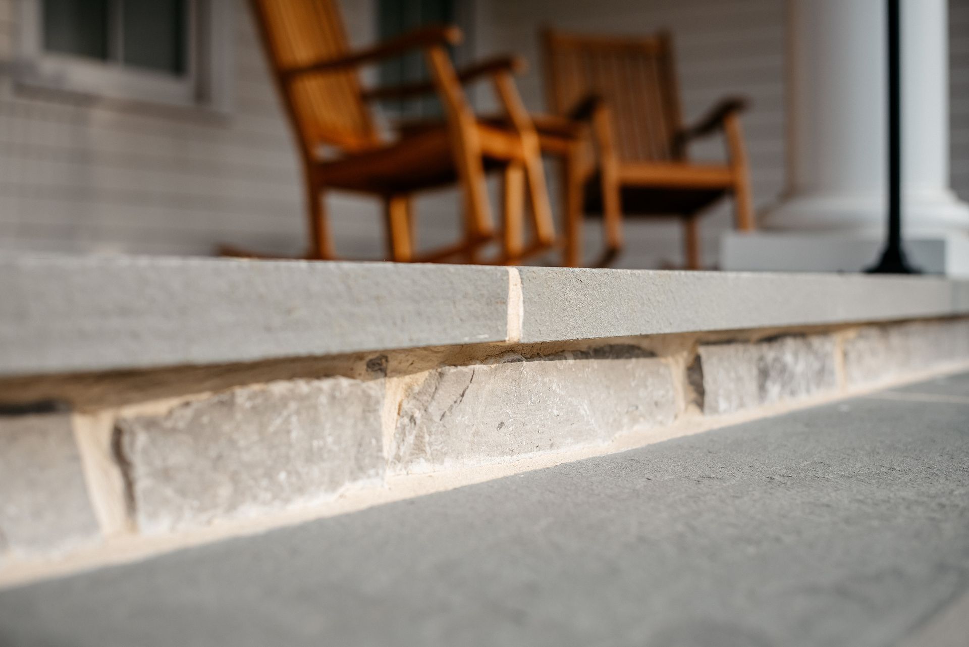Stone porch step with a wooden chair in the background