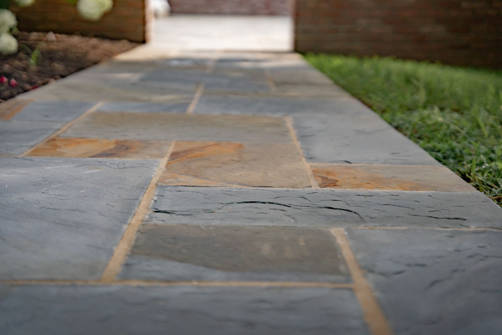 Stone garden walkway with rectangular tiles and grass along the sides