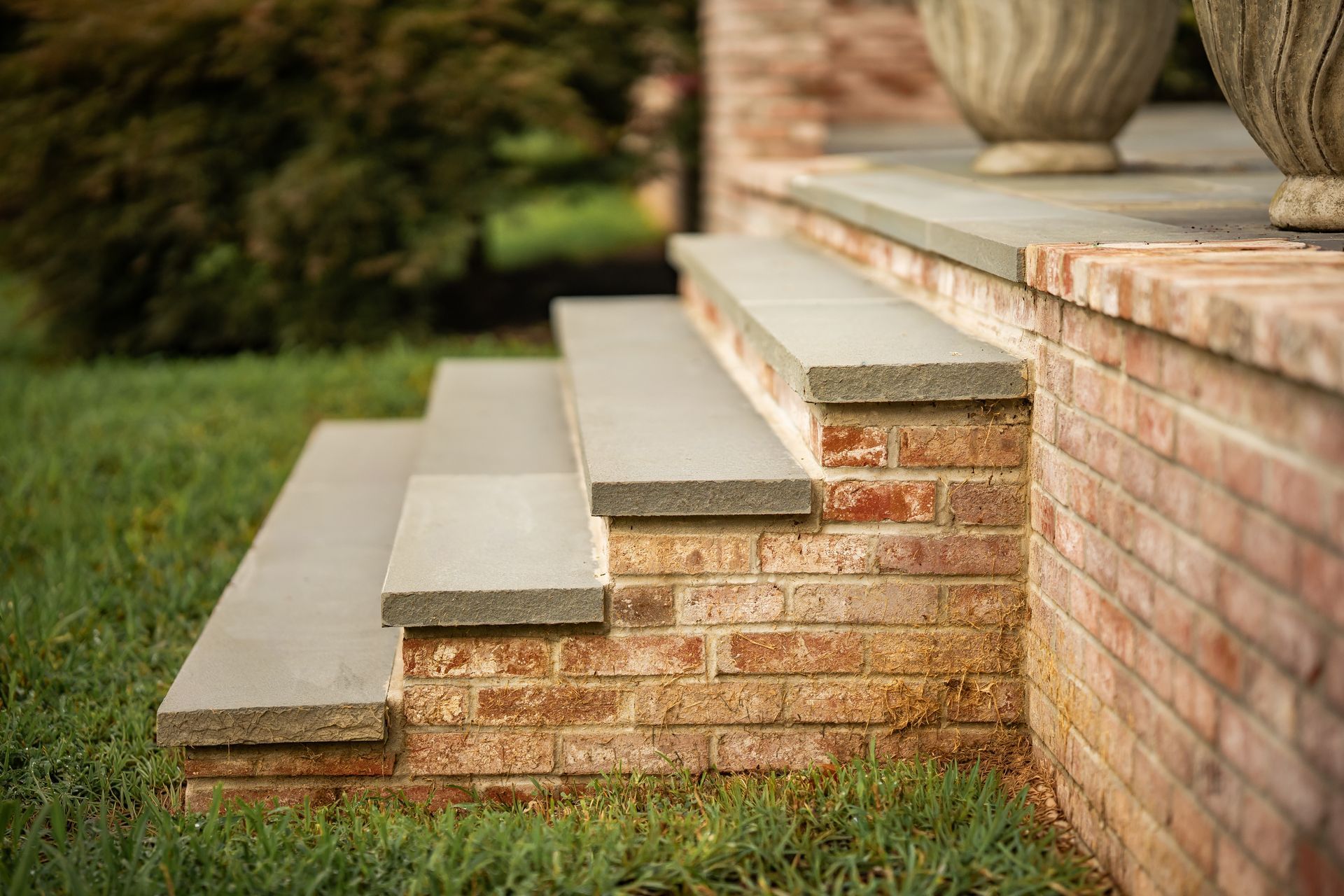 Brick steps with light stone treads beside a lawn and porch column