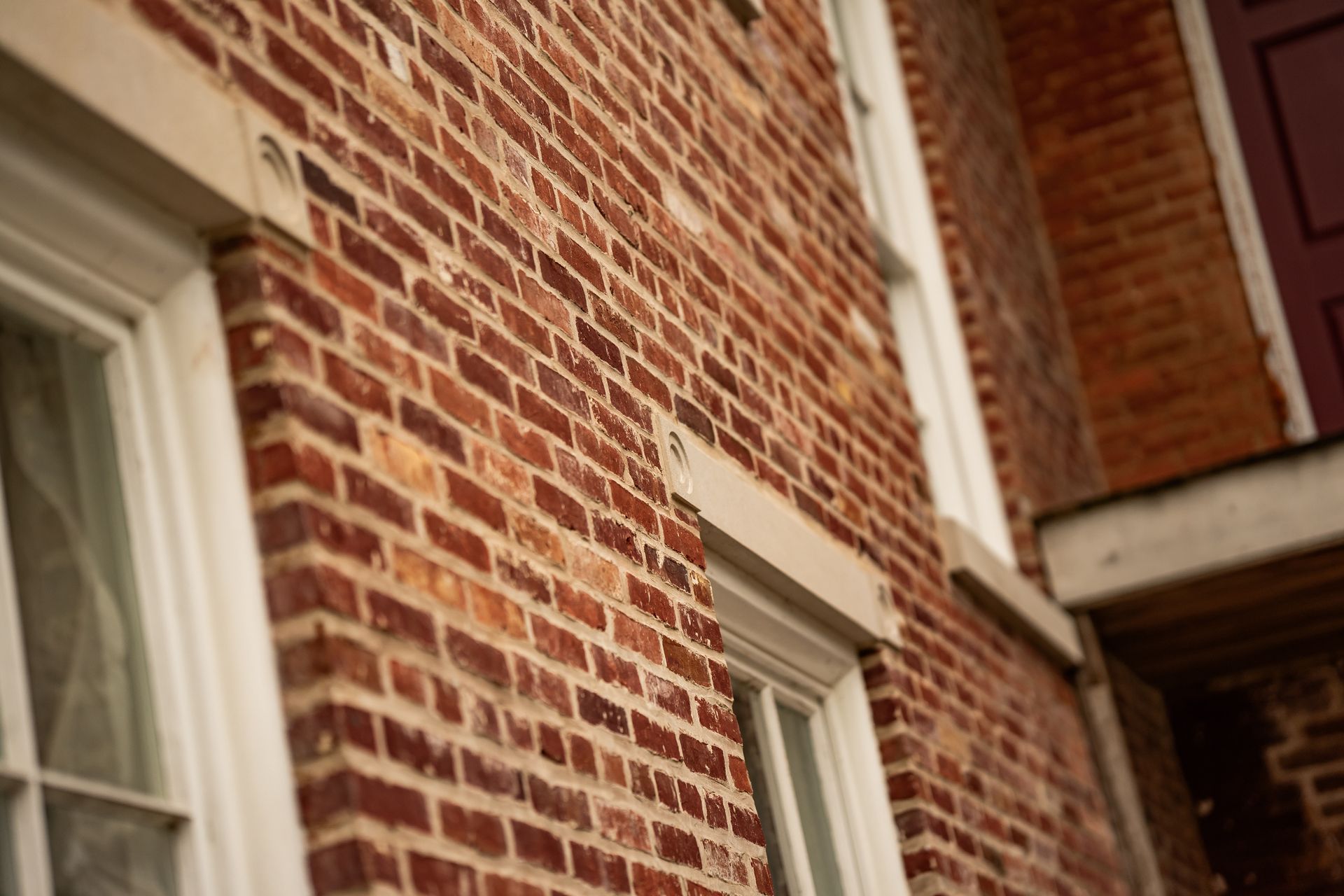 Brick building facade with white-trimmed windows and a small balcony.